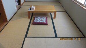 Een kamer met tatami matten, een houten tafel, een kussen en een zakdoos.