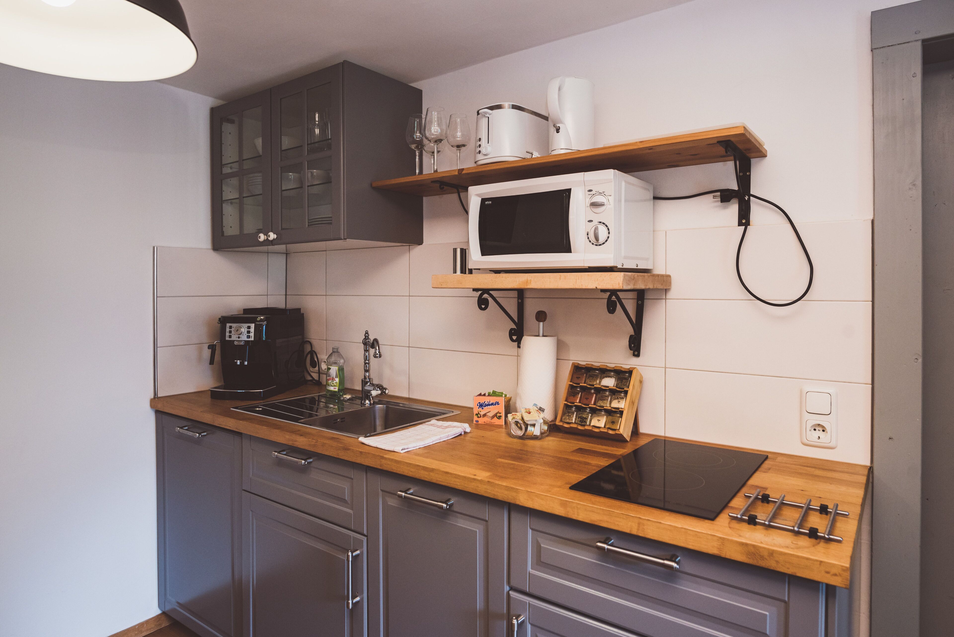 A kitchen with a wooden countertop, a microwave, a coffee maker, and a wine rack.