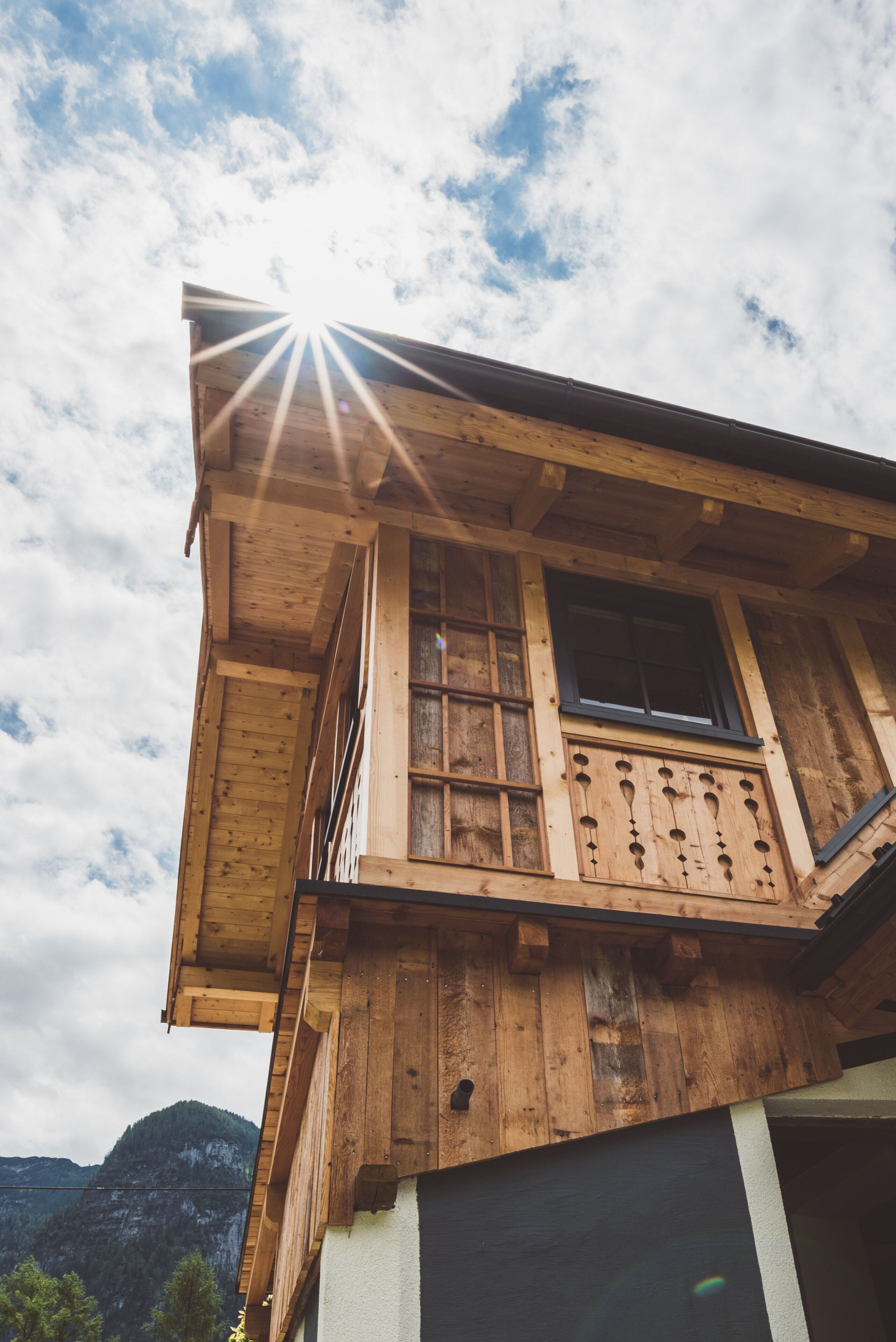 A wooden building with a balcony, a window, and a mountain in the background.