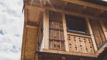 A wooden building with a balcony, a window, and a mountain in the background.