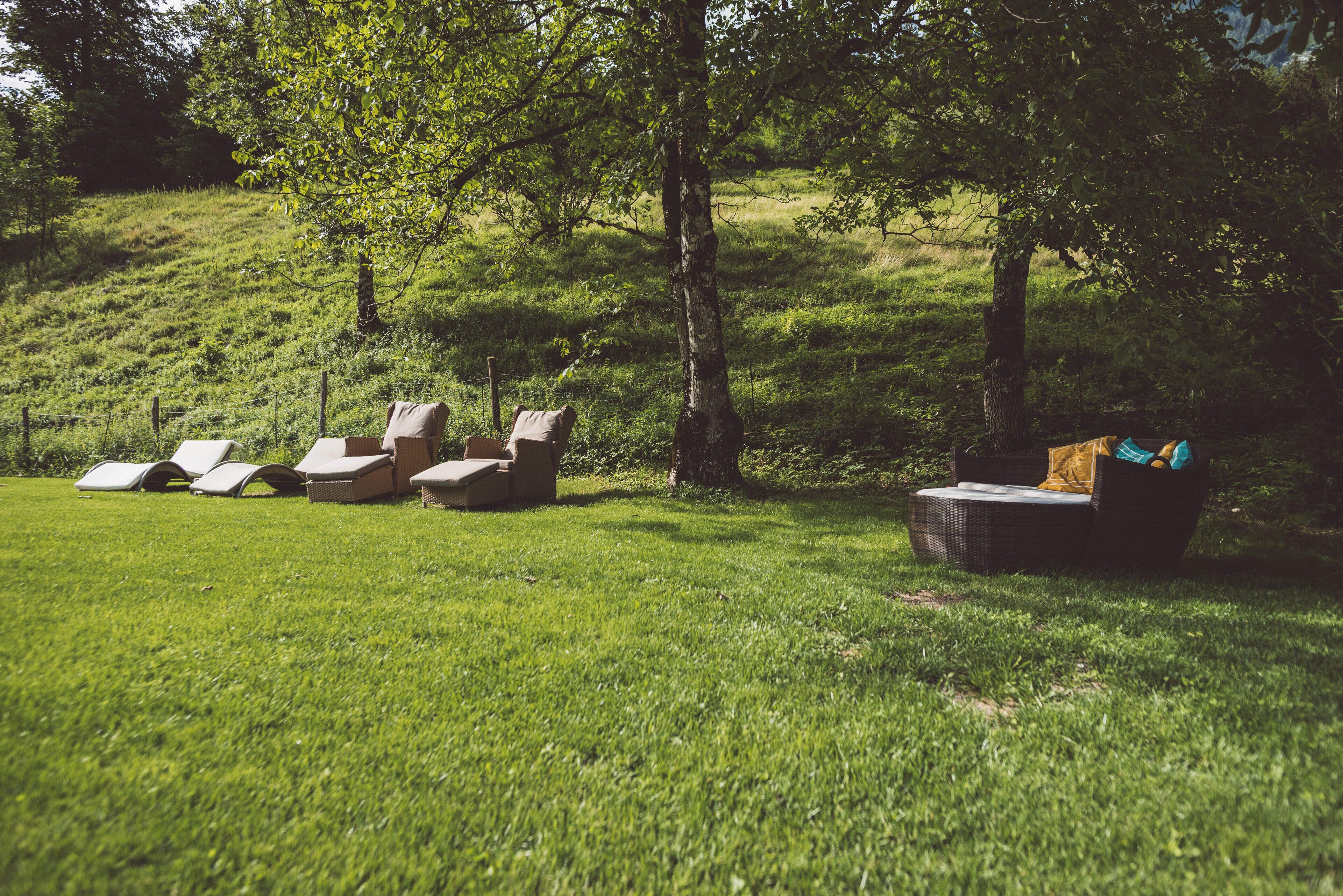 Een gazon met verschillende lounge stoelen en een rieten bank.