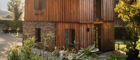 Ein Holzhaus mit Steinunterbau, geneigtem Dach und einer kleinen Veranda.