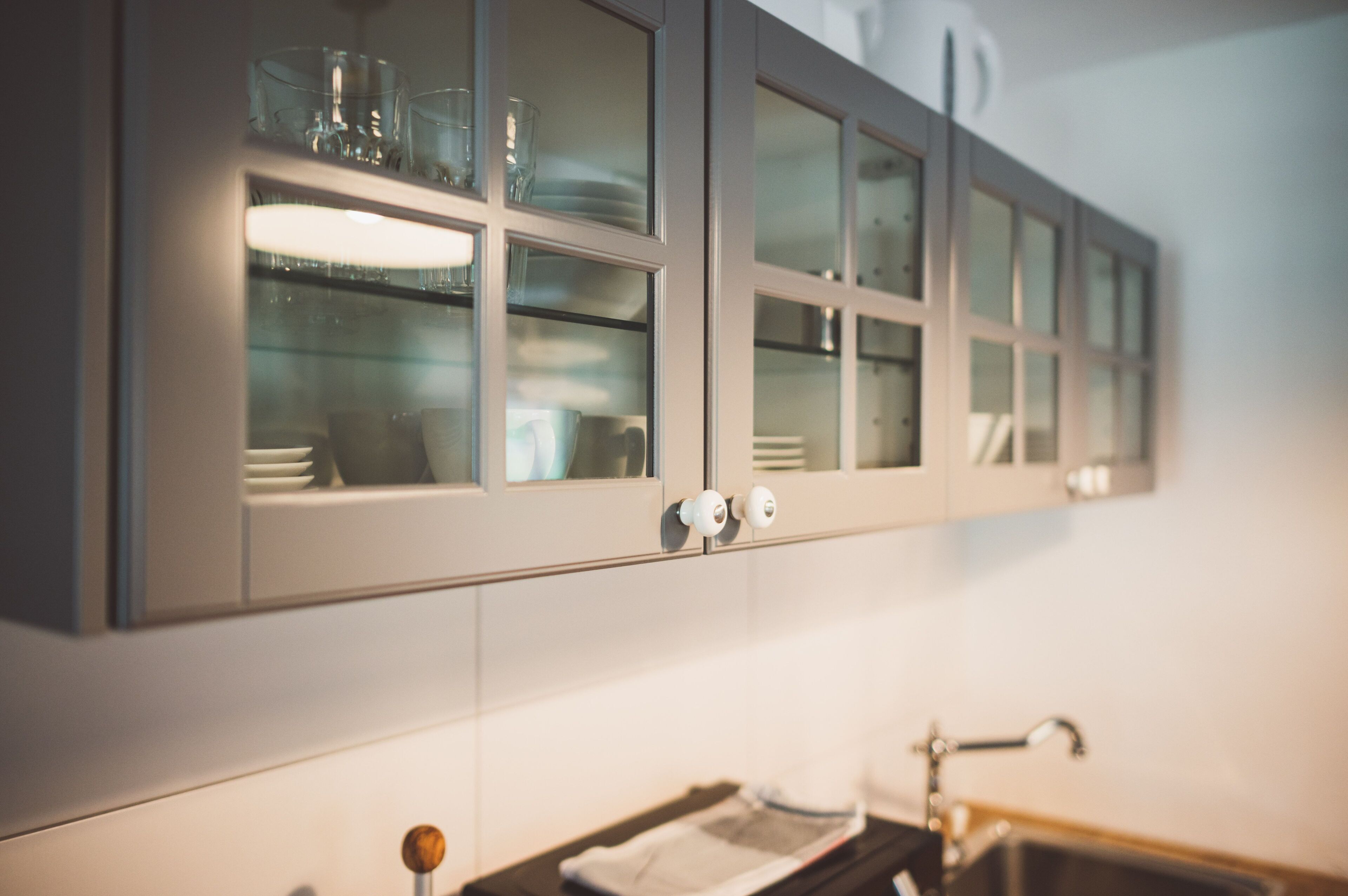 A kitchen with cabinets containing glassware and dishes.