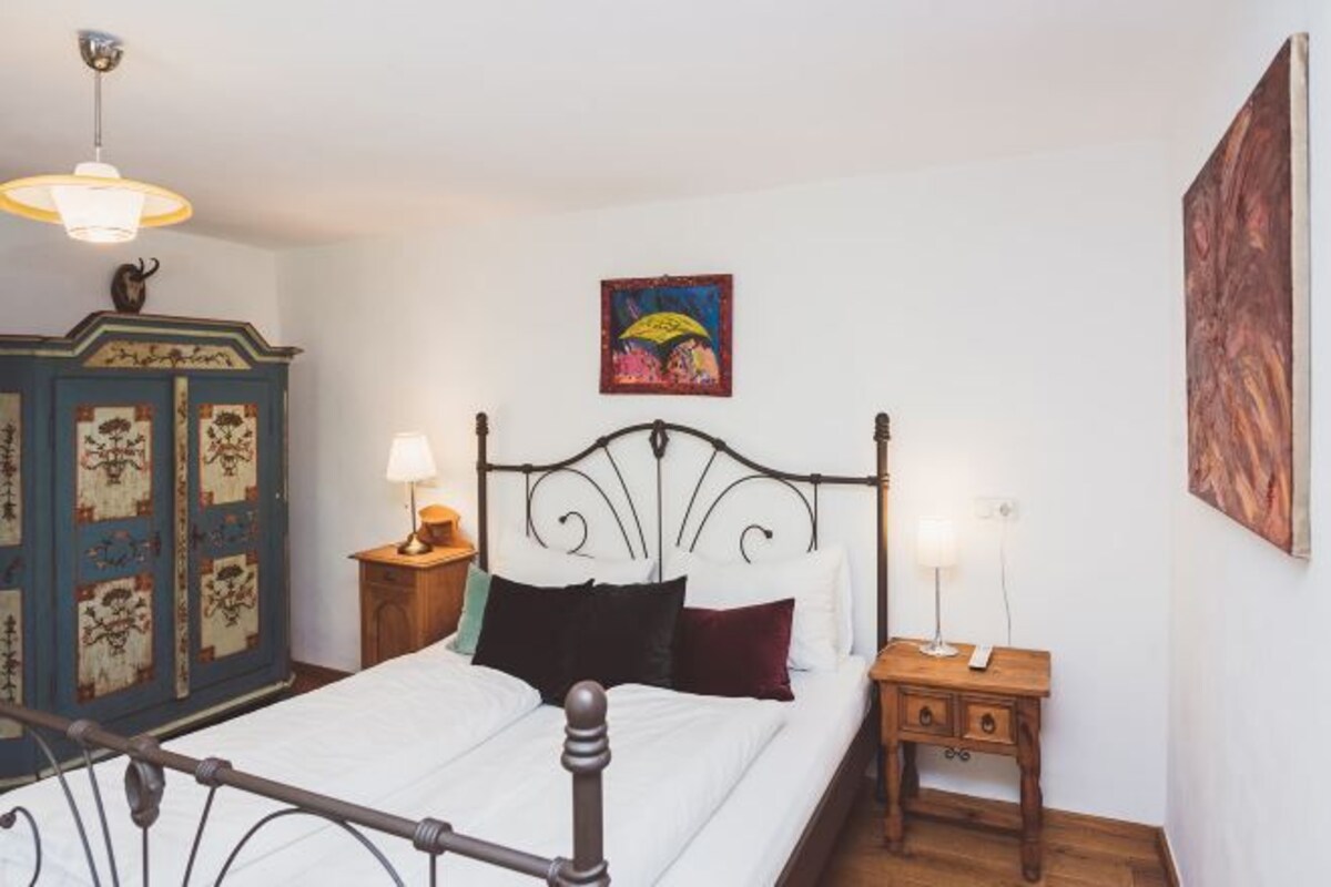 Un dormitorio con cama, armario, mesita de noche y un cuadro colgado en la pared.
