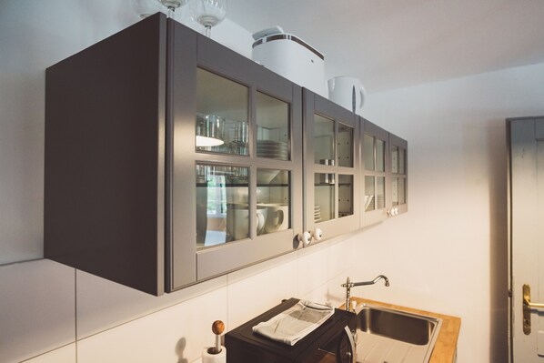 A modern kitchen with dark cabinets, a stainless steel sink, and a window above the cabinets. - Chalet am Sonnenhang (Obertraun)