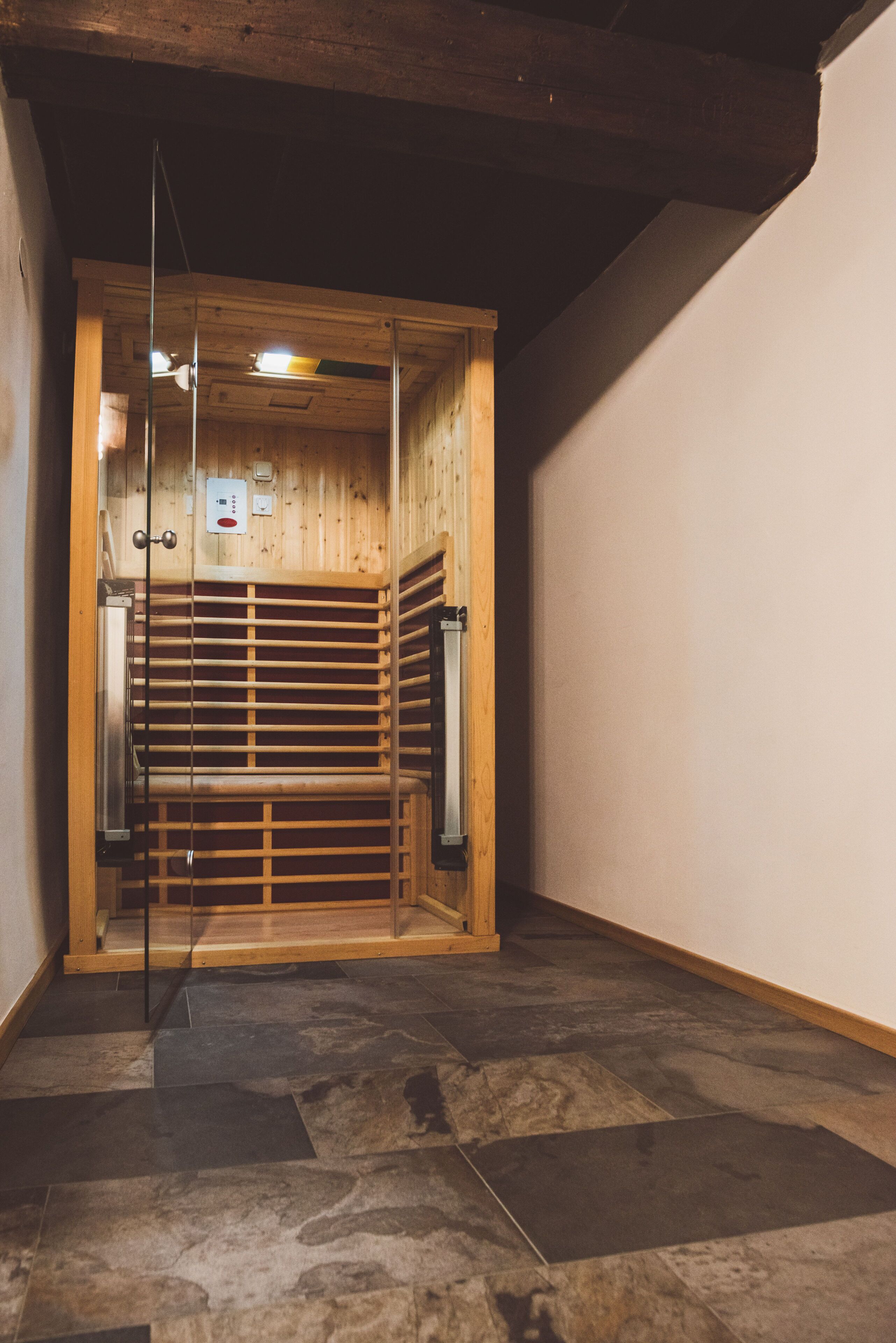 Un sauna avec un intérieur en bois, une porte en verre et un sol carrelé.