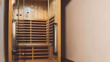 Un sauna avec un intérieur en bois, une porte en verre et un sol carrelé.