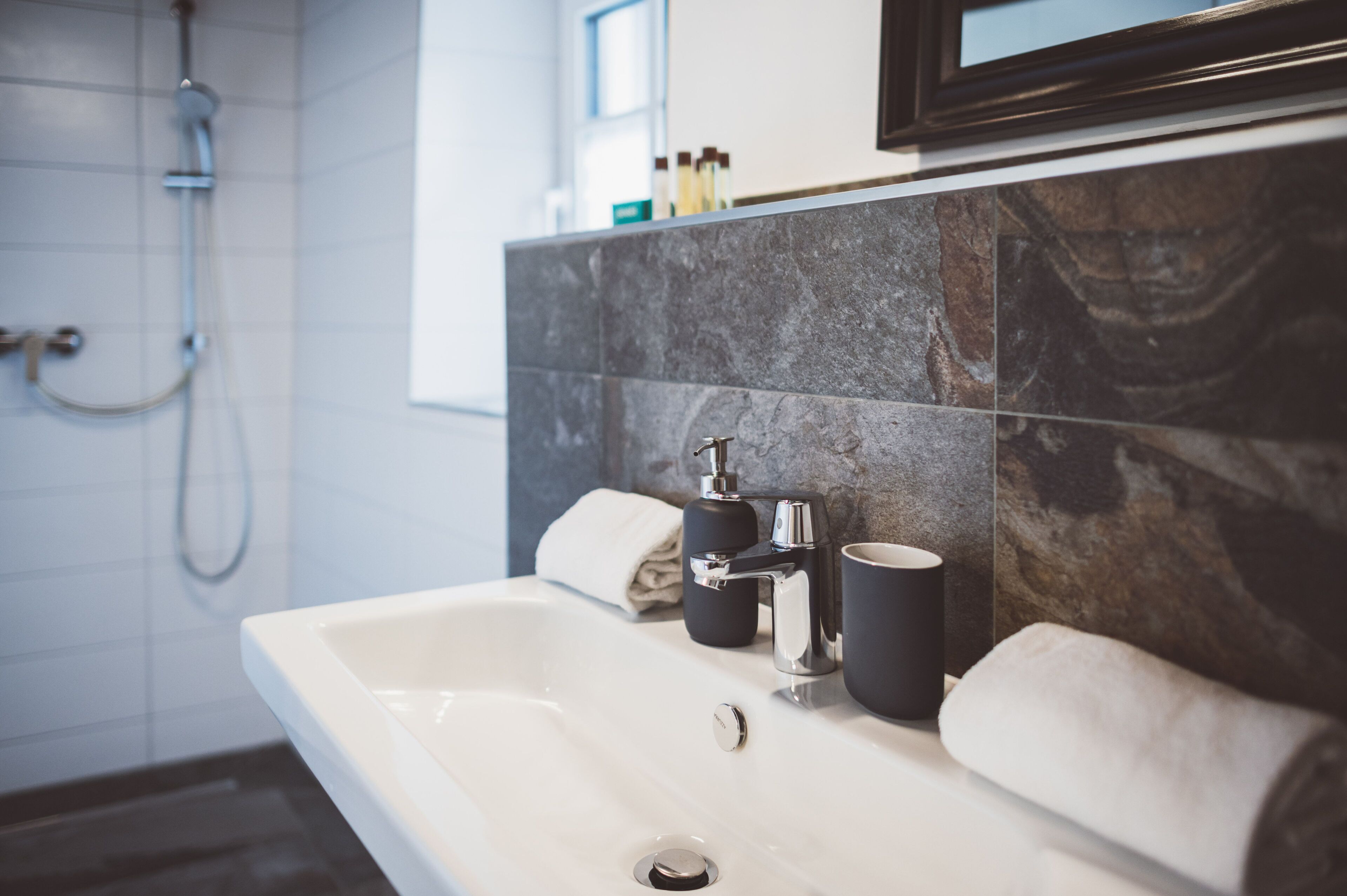 A bathroom with a white sink, black soap dispenser, and a towel.