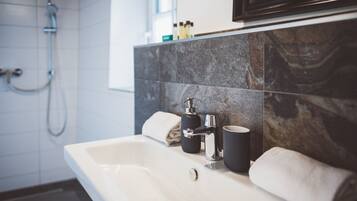 A bathroom with a white sink, black soap dispenser, and a towel.