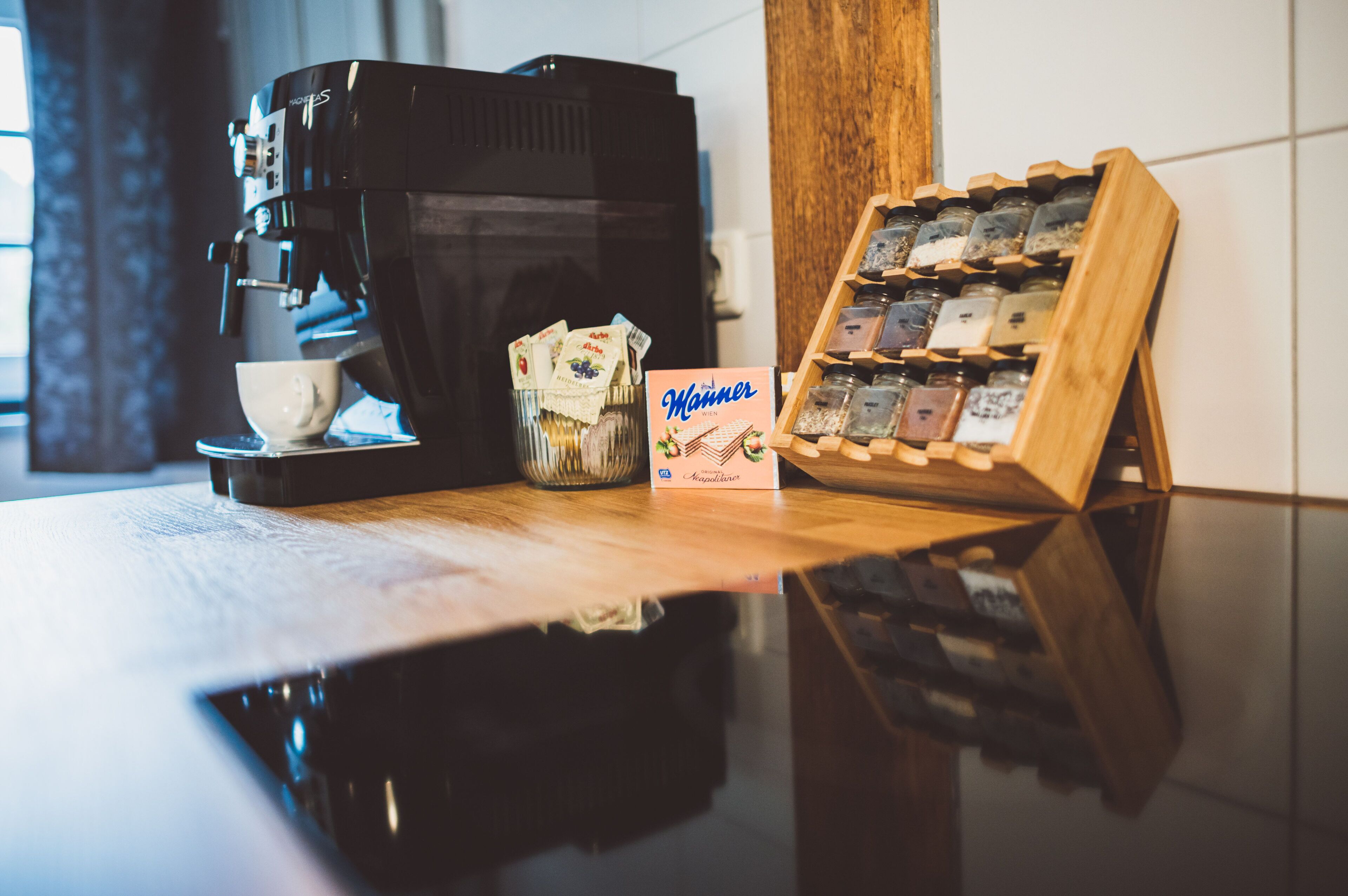 Een koffieapparaat, een kop en een presentatie van koffiebonen op een aanrecht.