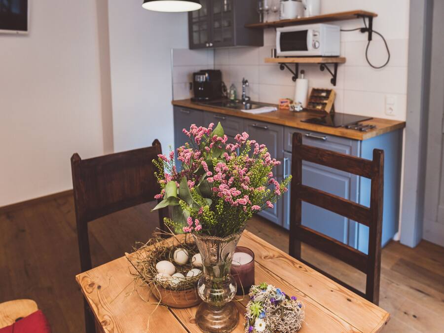 Una mesa de madera para comer con un florero, una vela y un nido con huevos.