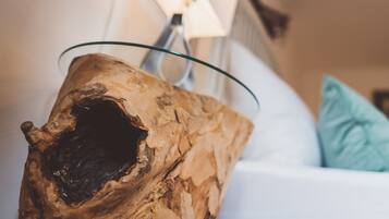 A piece of driftwood with a glass bowl on top, placed on a white sofa with a light blue pillow.