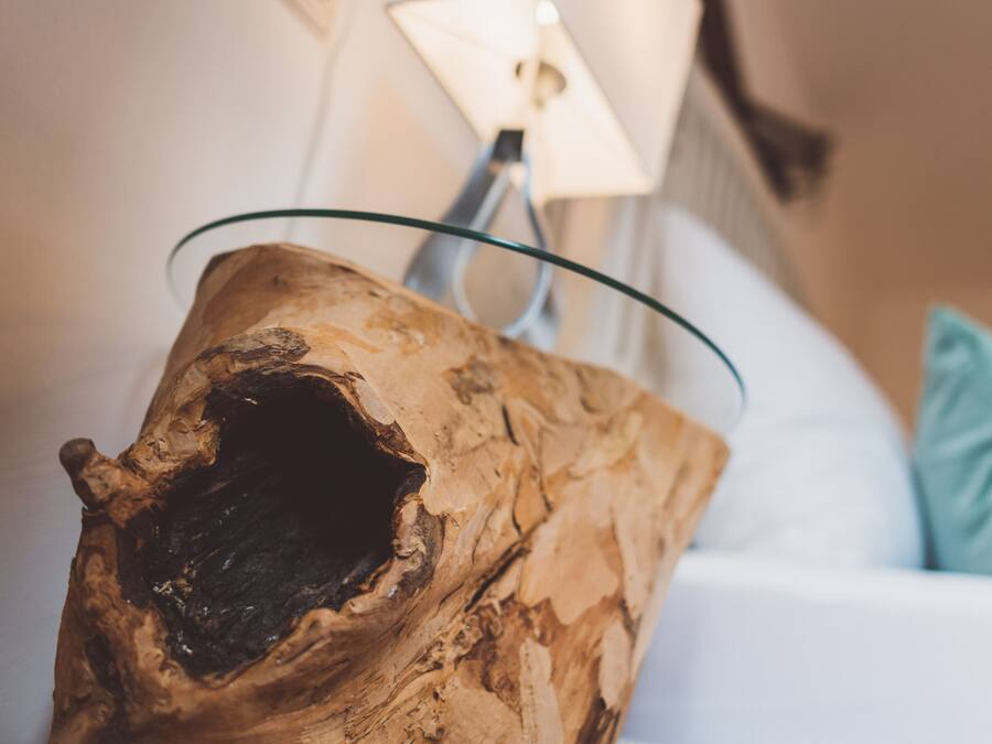 A piece of driftwood with a glass bowl on top, placed on a white sofa with a light blue pillow.