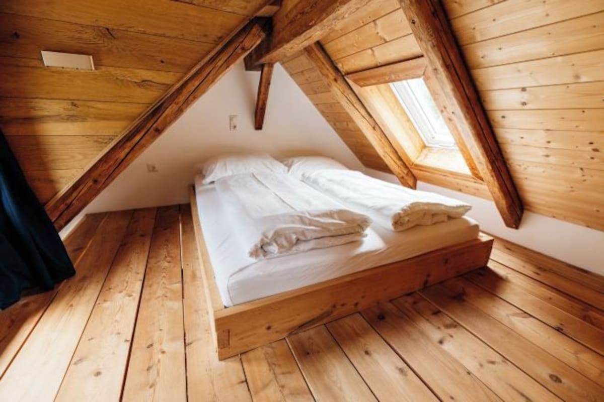 Dormitorio estilo loft con cama, techo inclinado y tragaluz.