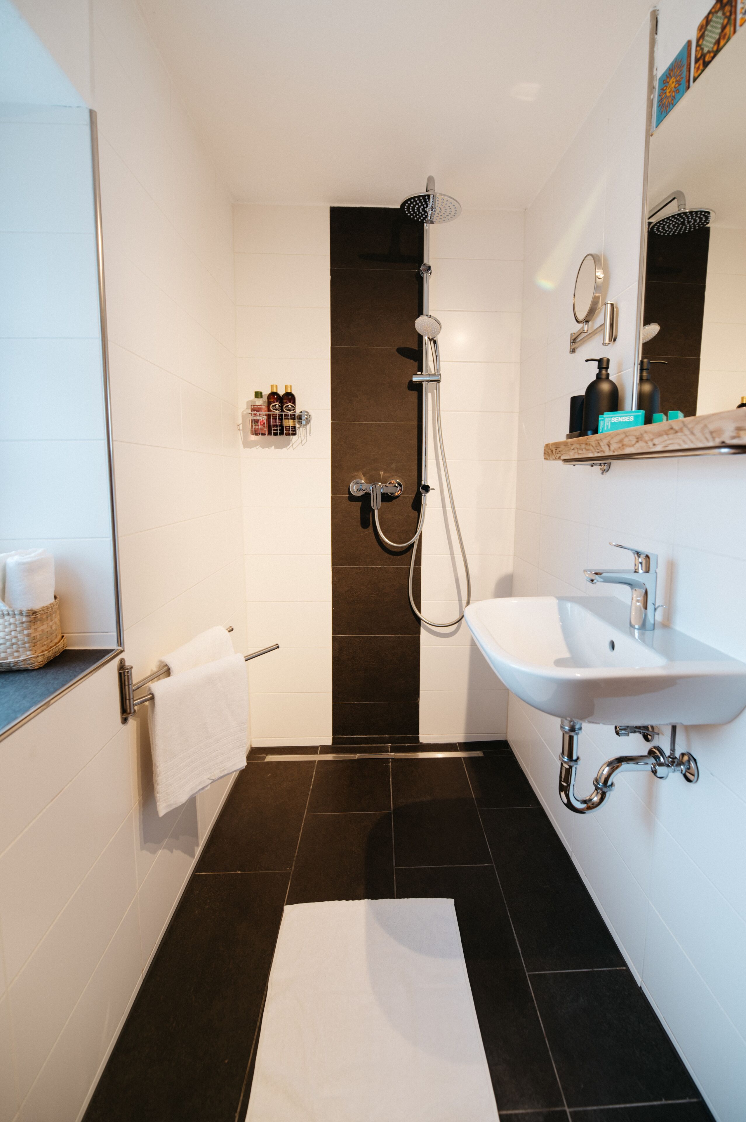 Un baño moderno con ducha, lavamanos y toallero.