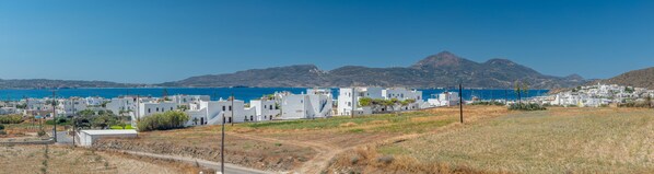A coastal town with white buildings, a clear blue sea, and a mountain range in the background. - Elea Milos (Milos)