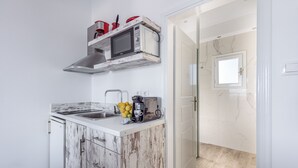 A compact kitchen with a built-in microwave, a coffee maker, and a sink. - Elea Milos (Milos)