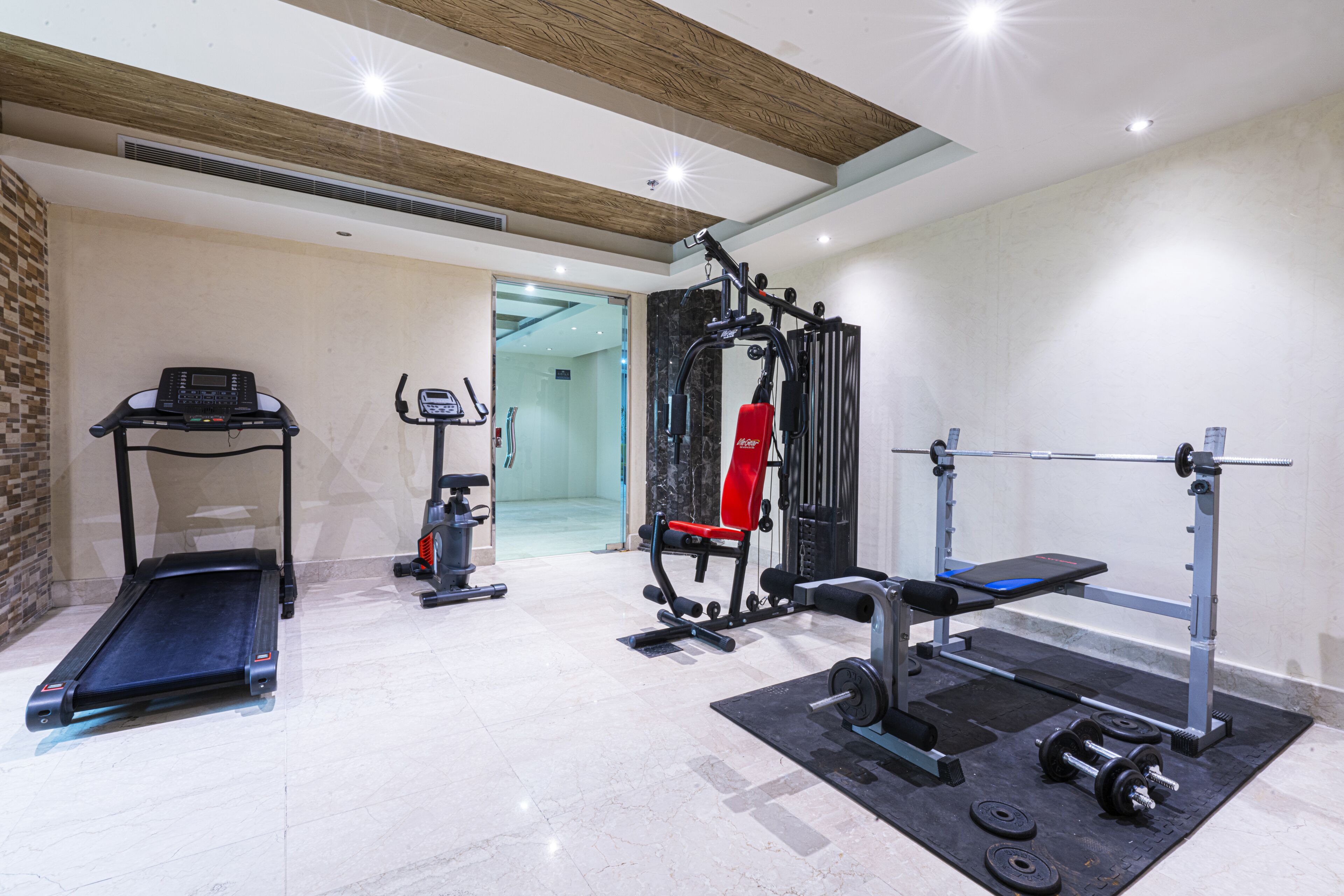 A gym with a treadmill, weight bench, and various exercise equipment.