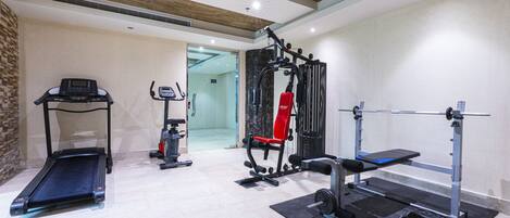 A gym with a treadmill, weight bench, and various exercise equipment.