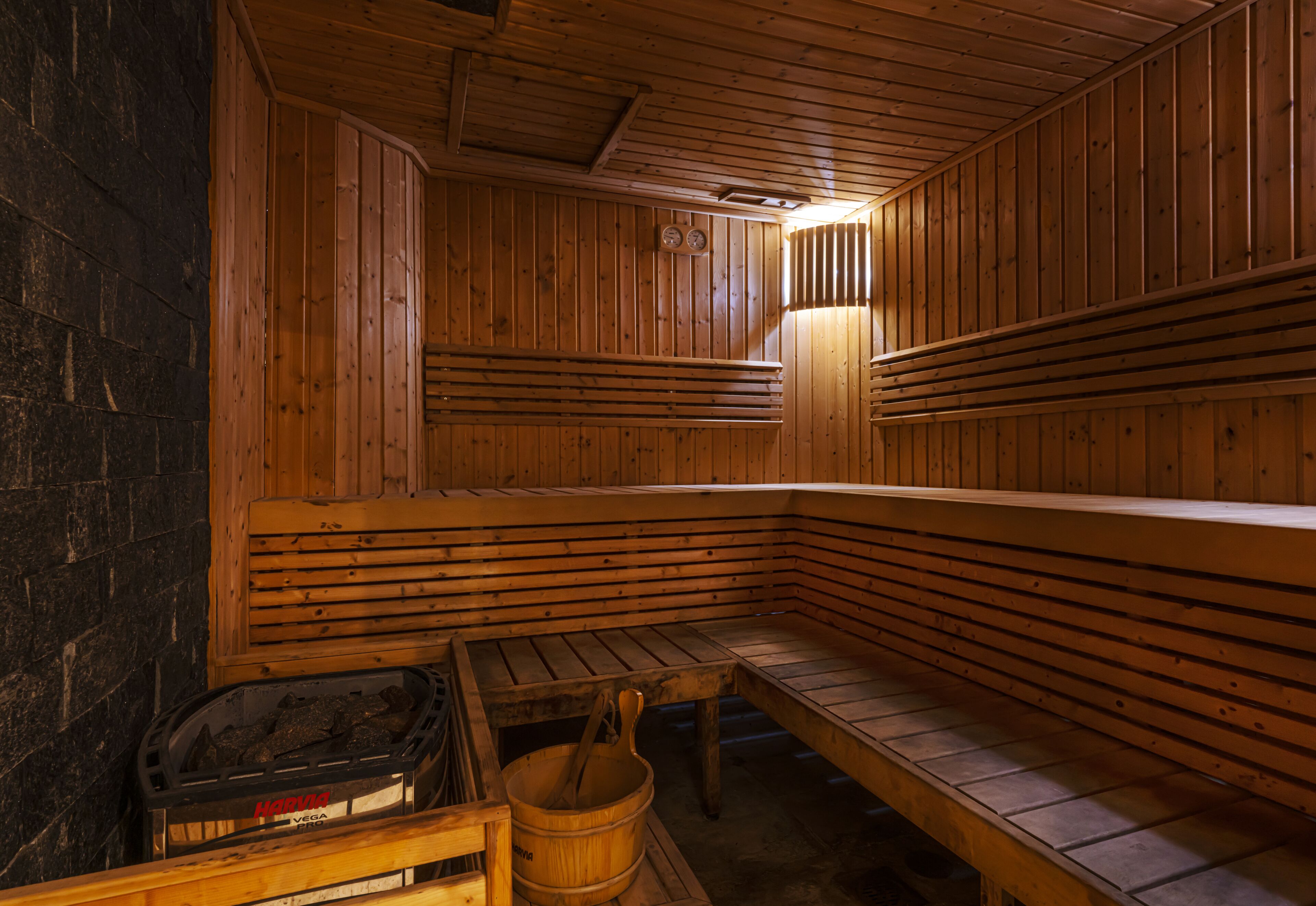 Una sauna con bancos de madera y un asiento con un cubo.