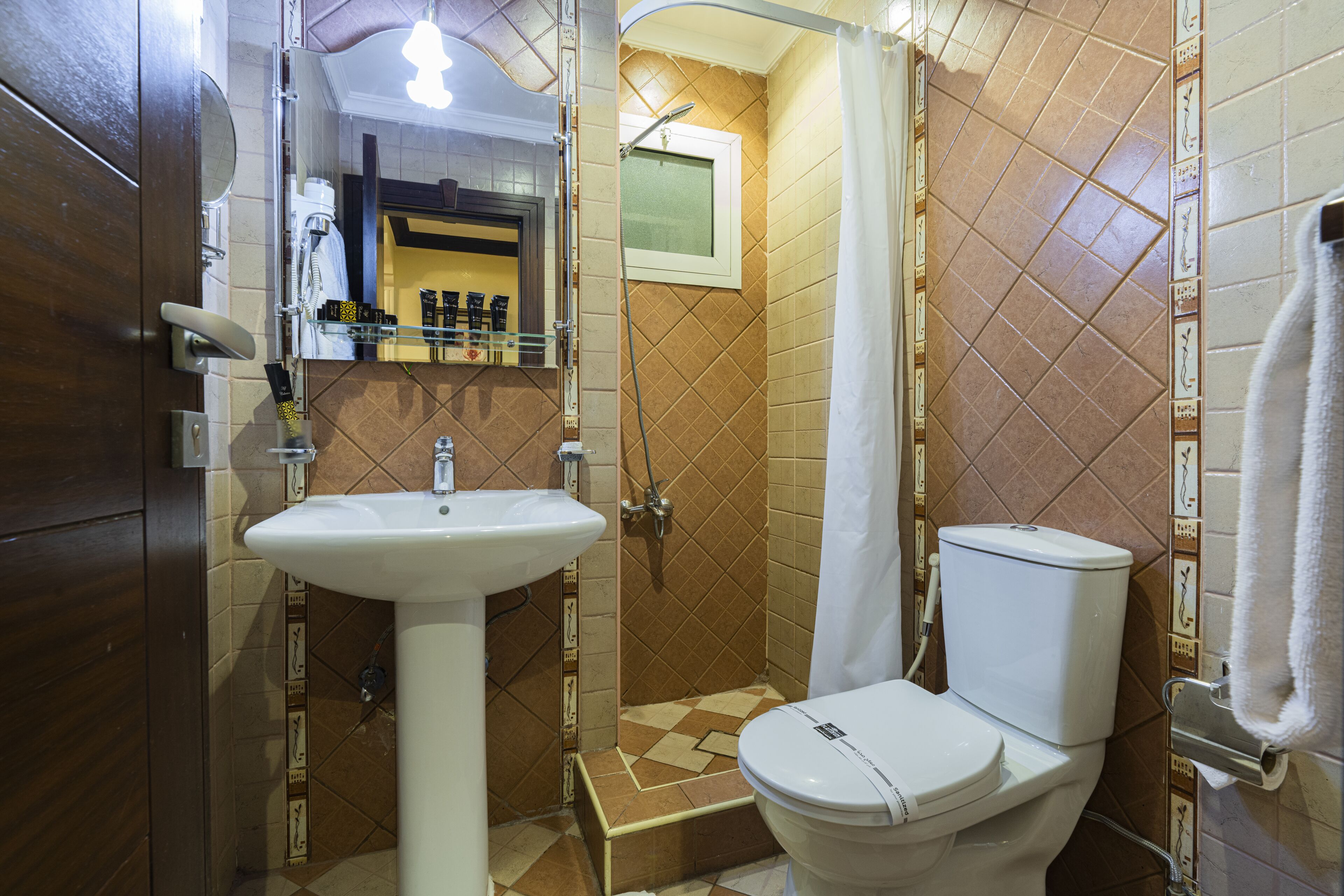 Un baño con lavamanos, inodoro, ducha y espejo.