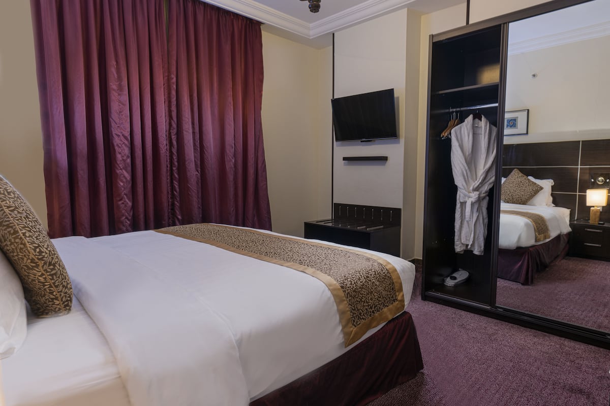 Una habitación de hotel con una cama, televisión, bata y espejo.