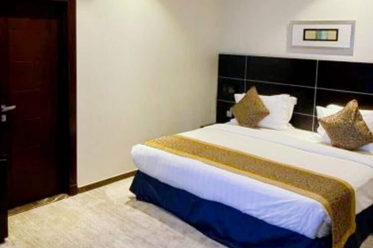 Una habitación de hotel con una cama grande, una puerta de madera y un televisor montado en la pared.