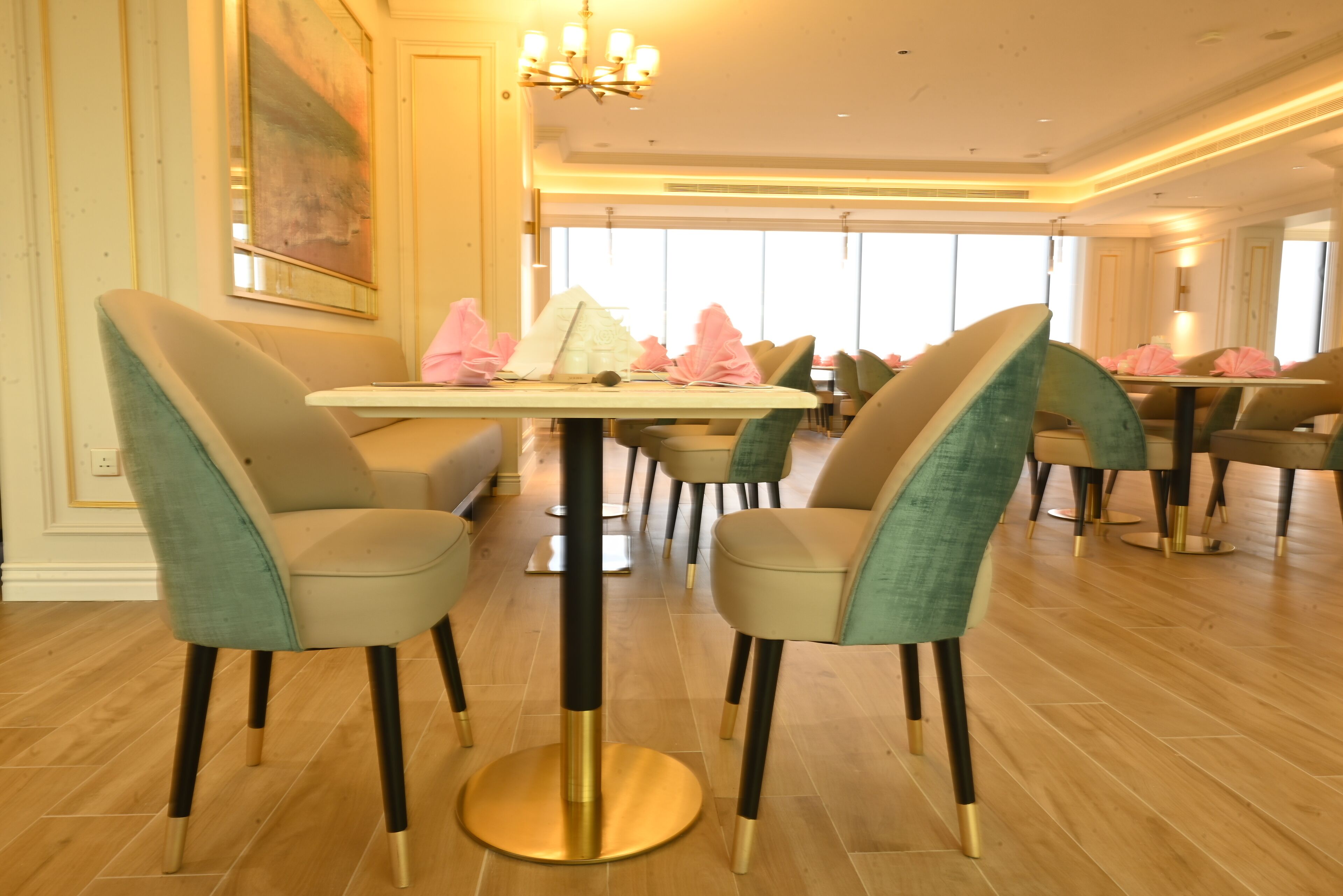 A dining area with round tables and chairs, a chandelier, and large windows.