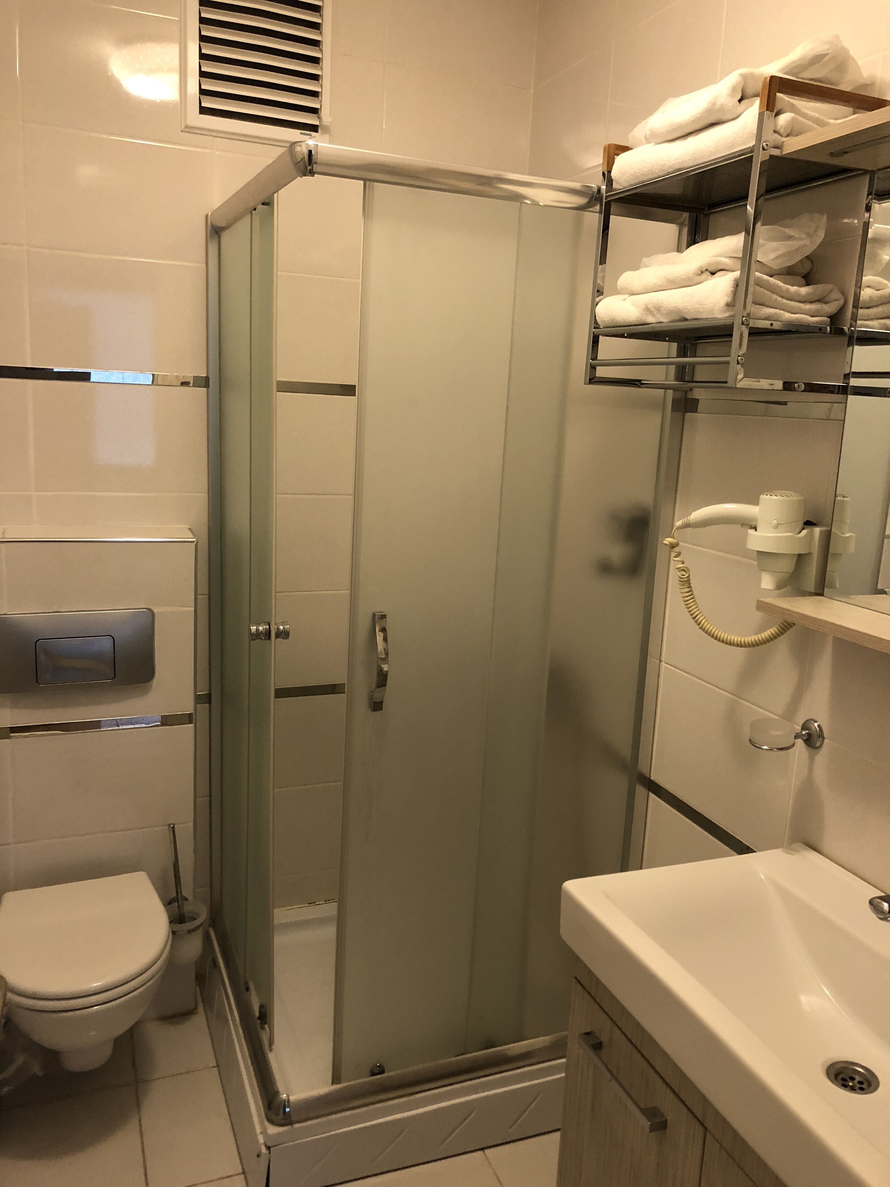 Un baño moderno con ducha envuelta en vidrio, inodoro y lavabo con tocador.