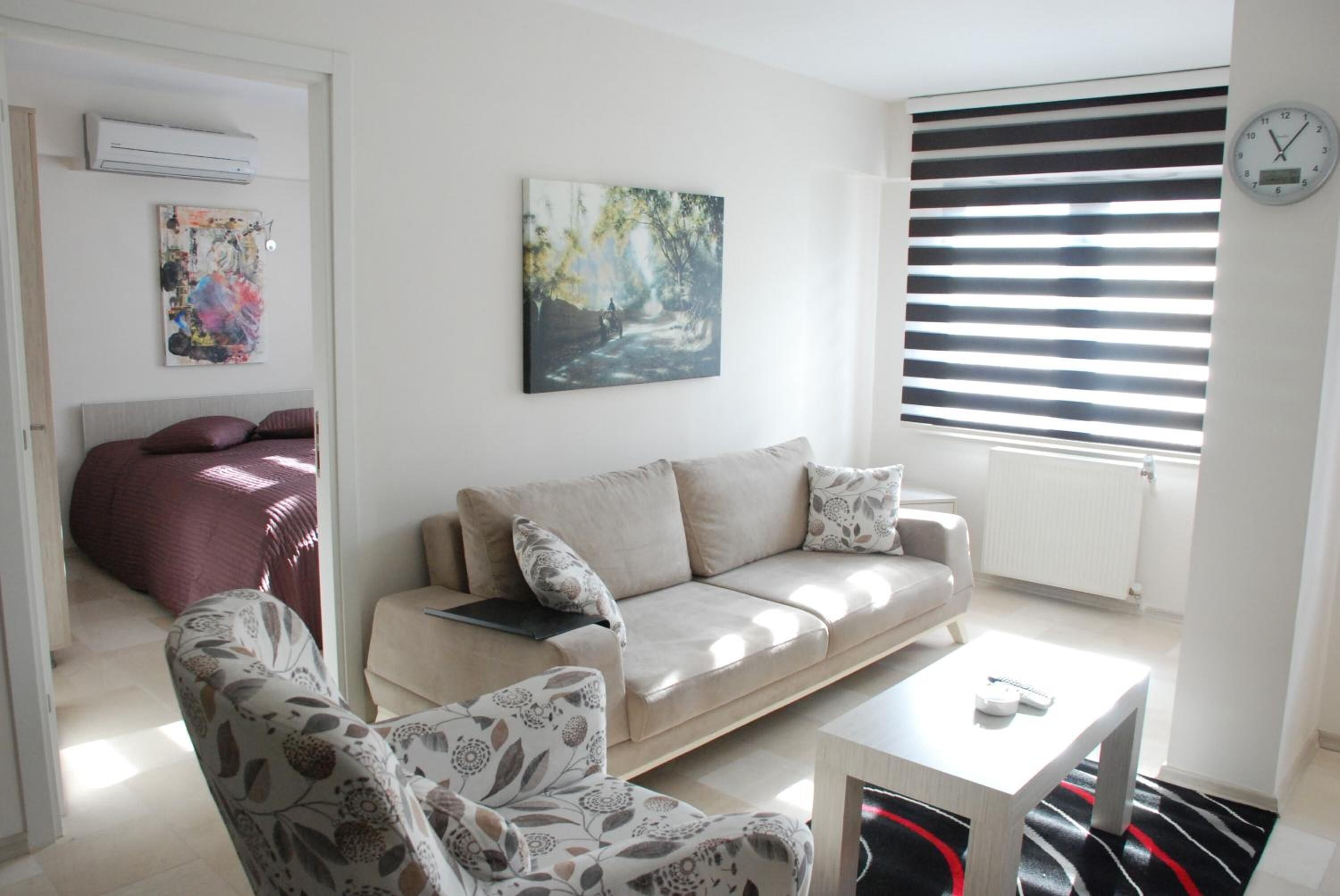 Una sala de estar con un sofá, sillones, una mesa de centro y un cuadro en la pared.