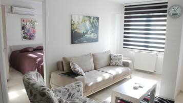 Una sala de estar con un sofá, sillones, una mesa de centro y un cuadro en la pared.