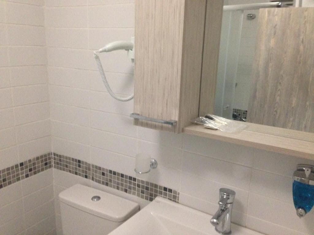 A bathroom with a toilet, sink, and mirror.