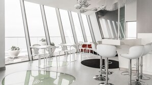 Un intérieur moderne avec une grande table en verre, des chaises blanches et un canapé rouge.