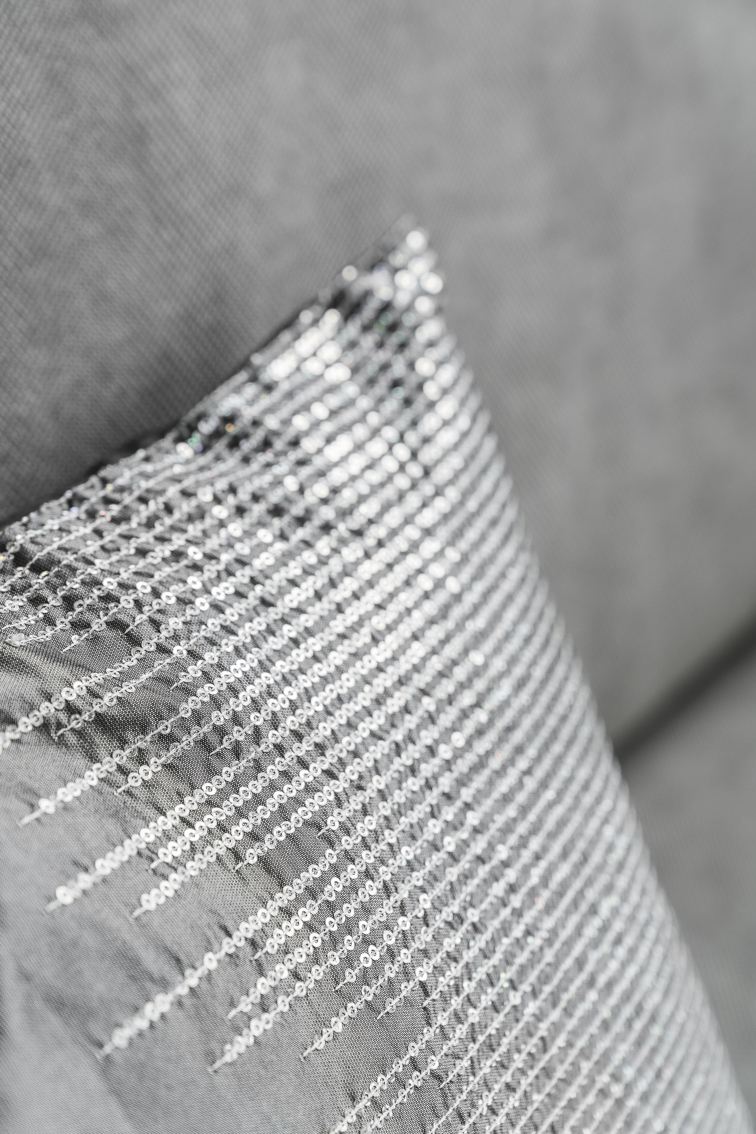 A close-up of a pillow with a textured fabric and a decorative, shiny border.