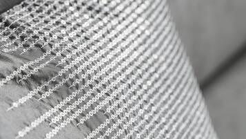 A close-up of a pillow with a textured fabric and a decorative, shiny border.