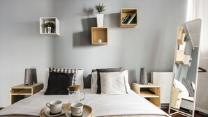 Une chambre à coucher bien rangée, avec un lit, des tables de chevet, une lampe de chevet, un miroir et un plateau avec des tasses.