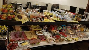A buffet table with various food items including fruits, pastries, cheeses, and meats.