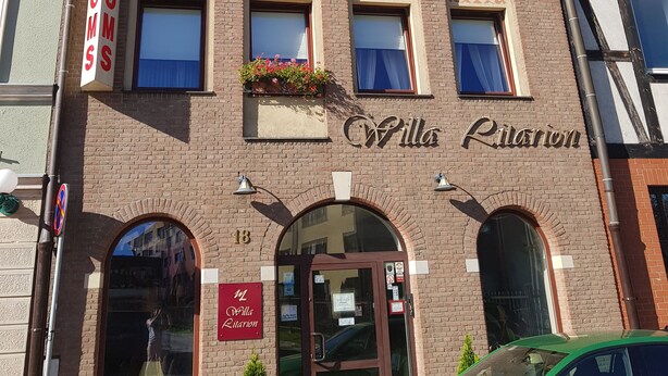 A building with a sign reading "Villa Ritairion" and a green car parked in front.