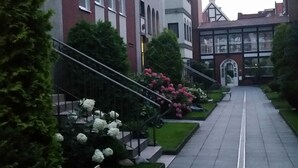 A pathway lined with benches and greenery, leading to a building with a traditional architectural style.