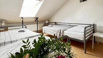 Un dormitorio con dos camas, un tragaluz, un escritorio pequeño y una silla.