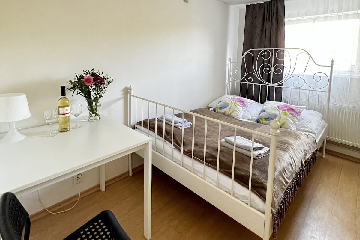 A bedroom with a single bed, a desk, a chair, and a window with curtains.