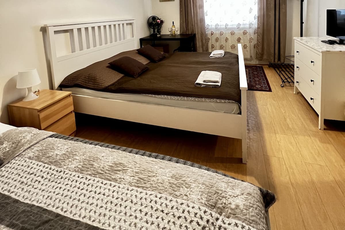 A neatly arranged bedroom with a bed, bedside table, lamp, and a dresser.