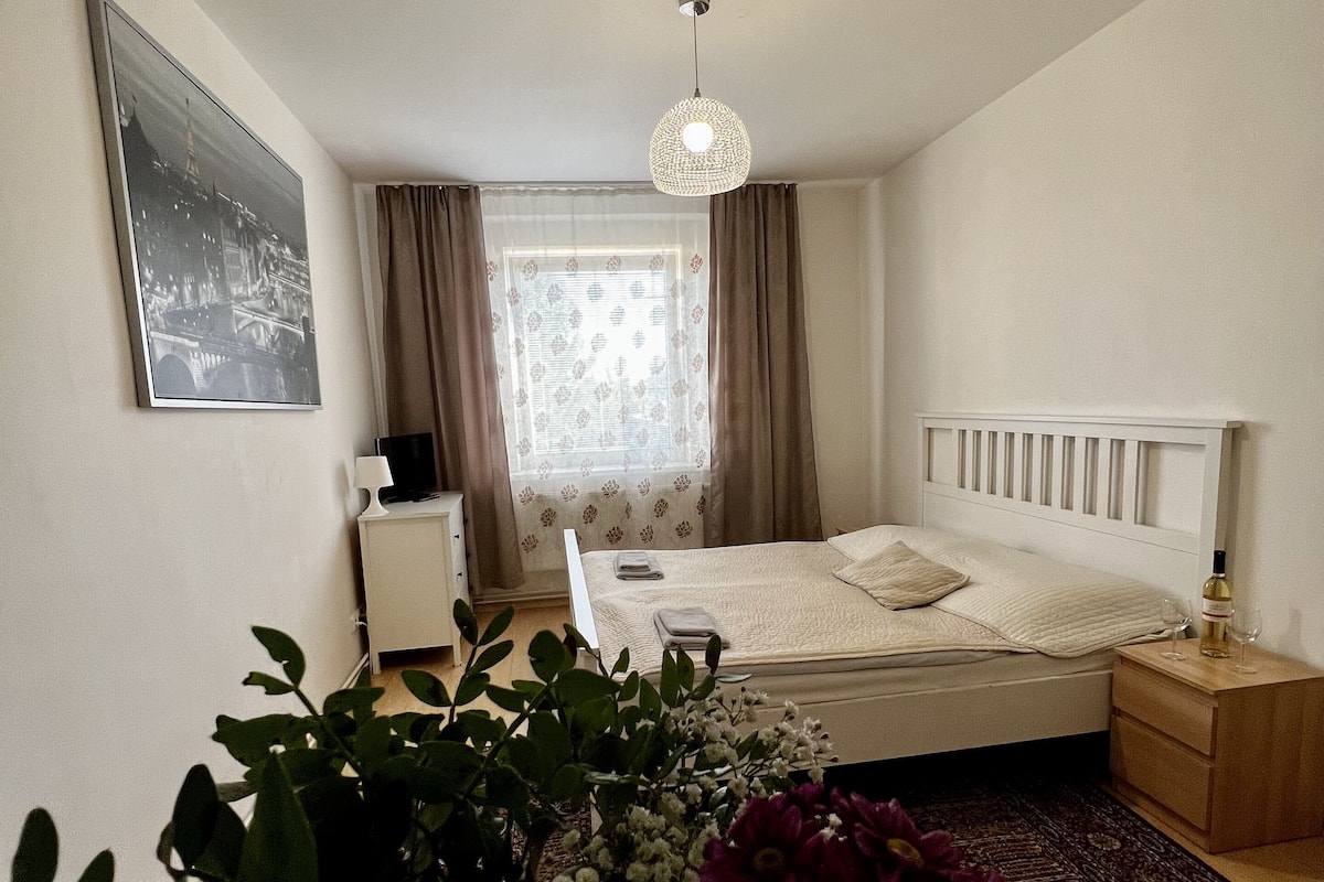 A bedroom with a bed, bedside table, lamp, and a hanging light fixture.