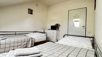 Una habitación con dos camas, un tocador pequeño y blanco, un espejo y un tragaluz.