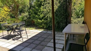 An outdoor patio with a table and chairs, surrounded by lush greenery. - Penzion Sofi (Prague)