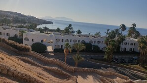 A coastal hotel with white architecture, palm trees, and a view of the sea. - Domina Coral Bay Vacation House (Sharm El Sheikh)