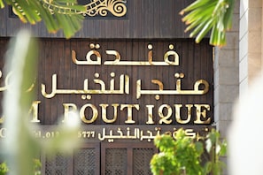A boutique hotel sign with Arabic and English text, indicating the name and contact number. - Palm Boutique Hotel (Jeddah)