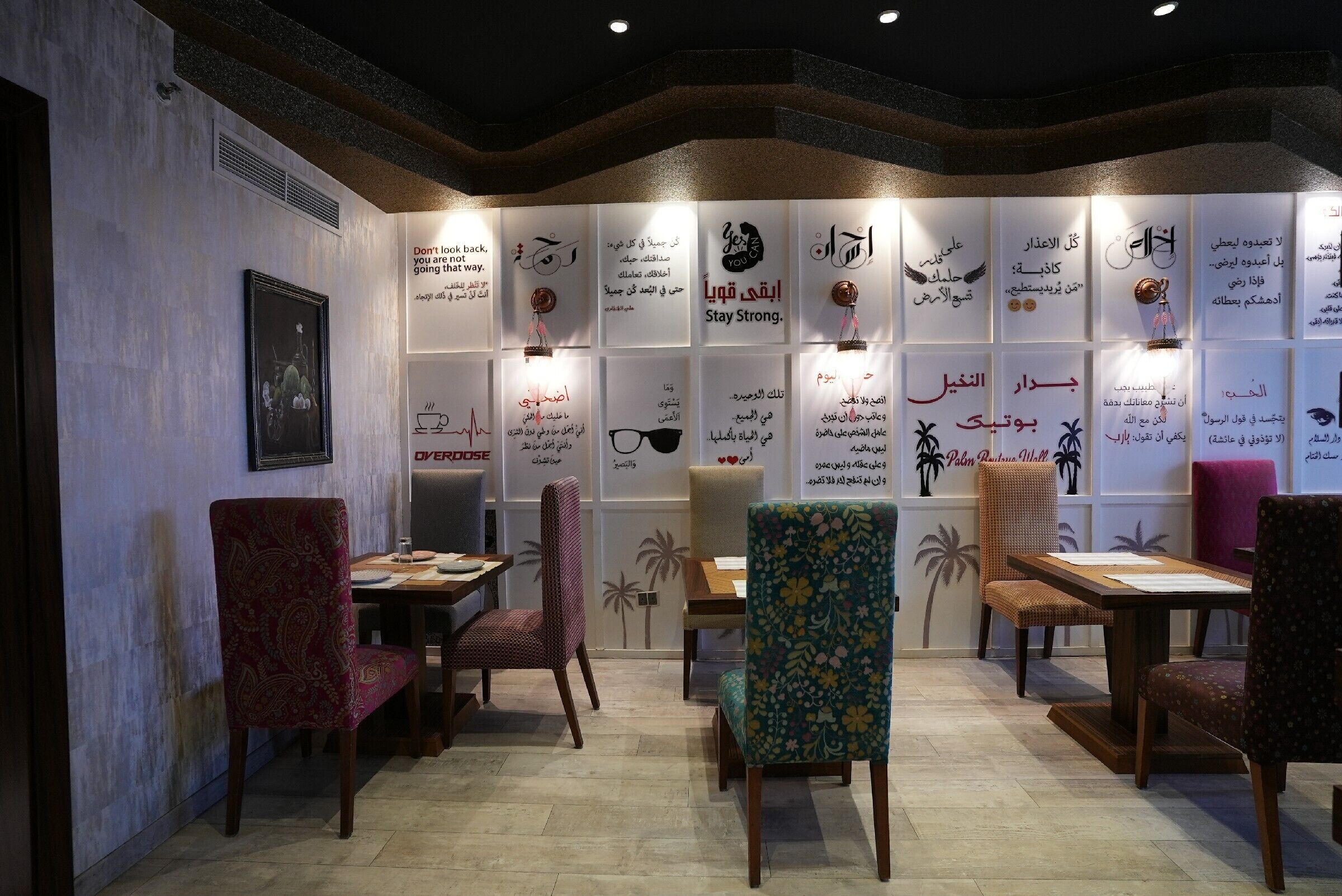 A restaurant interior with multiple tables and chairs, some with patterned upholstery.