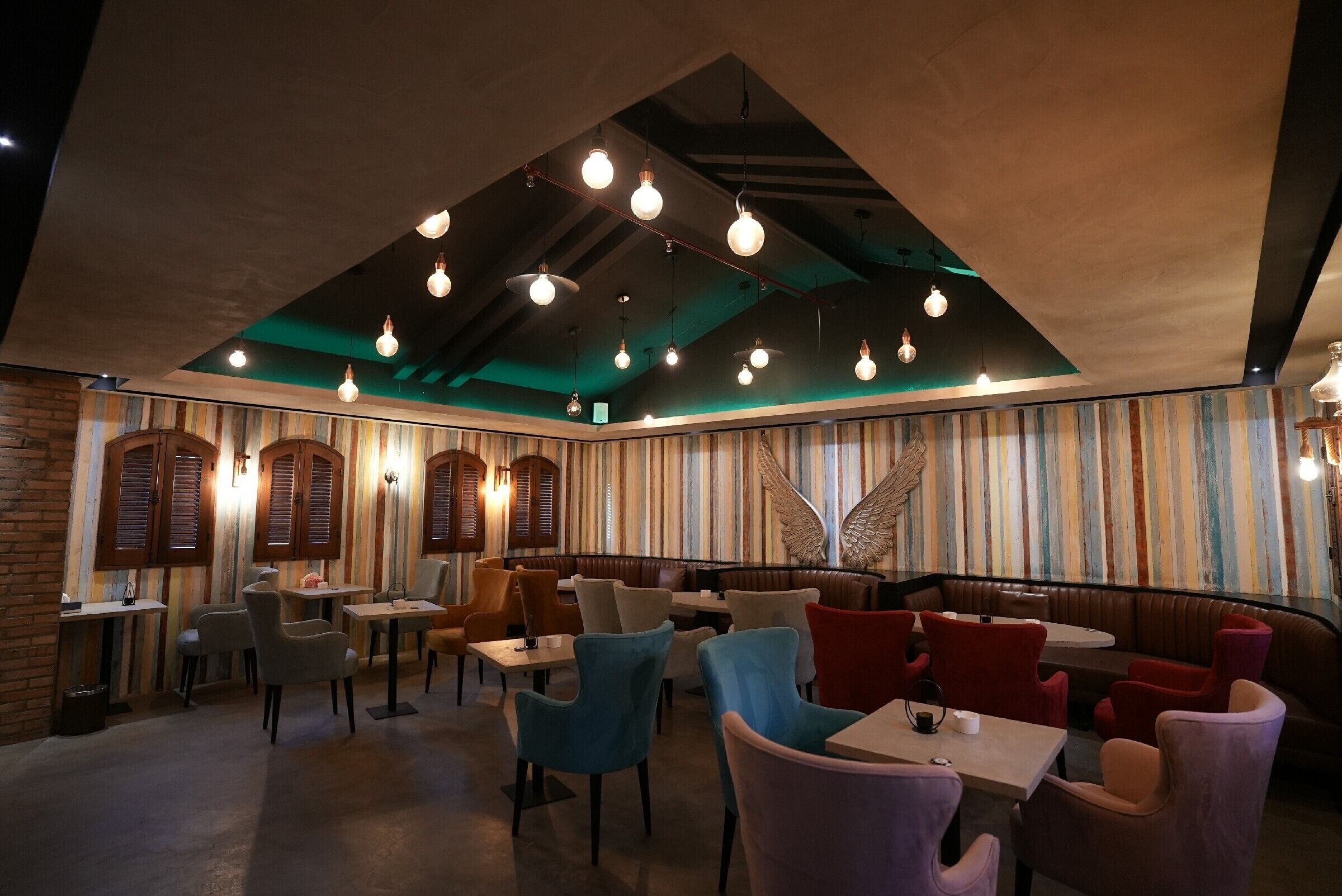 Interior de restaurante con cabinas, mesas y lámparas colgantes.