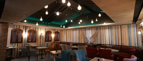 Interior de restaurante con cabinas, mesas y lámparas colgantes.